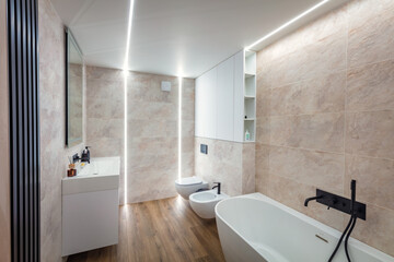 Modern bright bathroom with cupboard, white washbasin and bath, bowl, bidet and mirror. Comfortable toilet room with wooden floor.