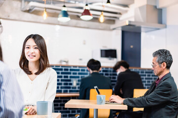 明るい雰囲気の社員食堂でランチを取るオフィスワーカー