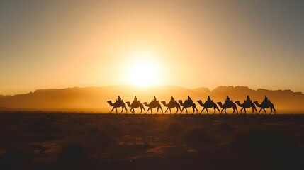 Fototapeta na wymiar Silhouetted caravan of camels crossing desert at sunset.