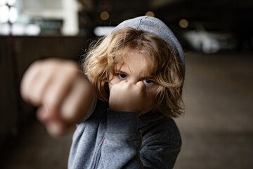 Aggressive child fight. Little kid boy fighting outside. Angry little boy showing fist. Portrait of...
