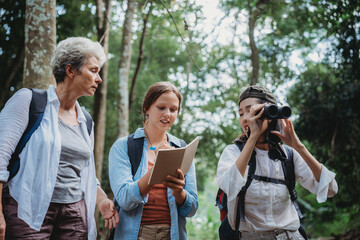 woman family walking in the forest to watching a bird in nature, using binocular for birding by...