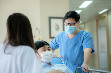 Asian male doctor helping, caring, encouraging or comfort patient at the bed before doing a surgery in operating room. A friendly doctor team helping and talking or supporting patient after recovering