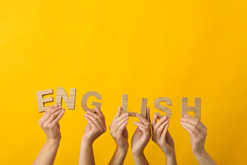 The word "English" in the hands of people, on a yellow background.