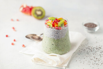Matcha chia puddind with fruit berry salad in glass on bright background. Healthy breakfast