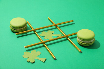 Paper clover leaves, macaroons, and cocktail straws on green background, close up