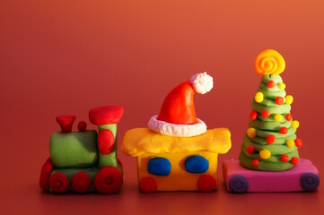 A toy train with a Christmas tree and a Santa Claus hat. Christmas decorations. Color background.