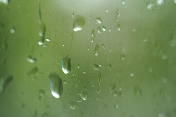 Drops on the window pane. Background image. Green tone.
