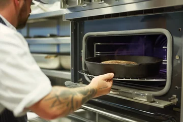 Photo sur Aluminium Boulangerie chef placing a castiron bread pan in a commercial oven