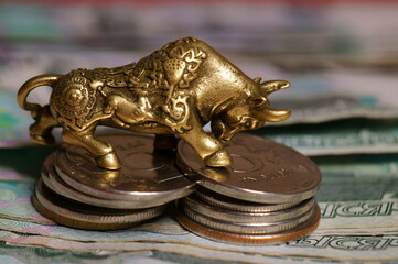 A metal bull with coins and money on the table.