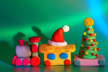 Obraz premium A toy train with a Christmas tree and a Santa Claus hat. Christmas decorations. Green background.