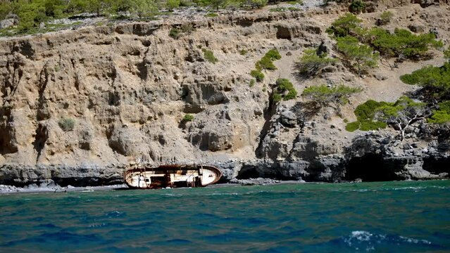 Refugee Shipwreck on the beach of Asterousia in Crete, rocks of geological interest at background