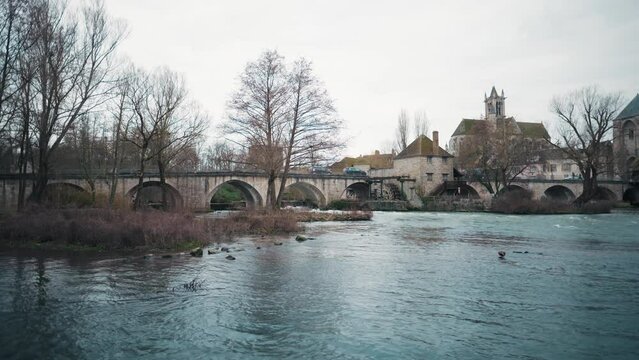Profile view of Moret sur Loing city under cloudy sky in France. Waterfront.