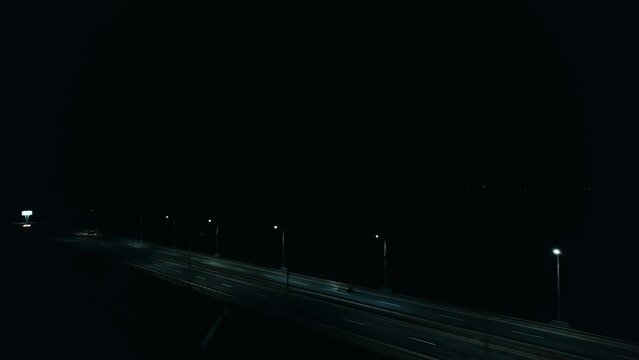 Aerial view of movement of motorcyclist and cars with headlights on on night highway and with lanterns along road