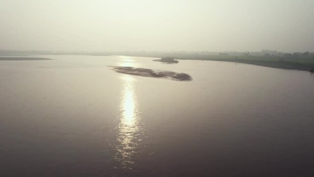 Dreamy aerial view of sunlight reflection in the muddy Chenab river in Pakistan.