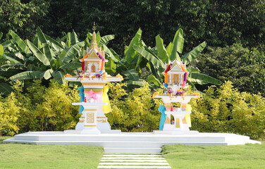 Traditional Thai spirit houses with green garden background.
