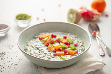 Matcha chia puddind with fruit berry salad in bowl on grey background. Healthy breakfast