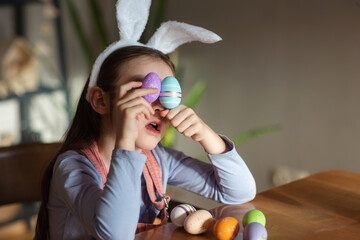 child girl playing with Easter eggs at table at home