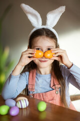 funny child girl playing with Easter eggs at table at home