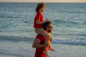 Father and son boy walking on beach. Summer holiday. Father and son enjoying summer vacation...
