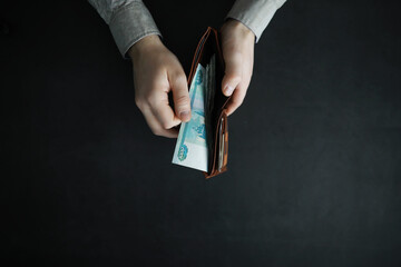 Hands take out cash banknotes from a wallet on a gray background. Foreign currency.