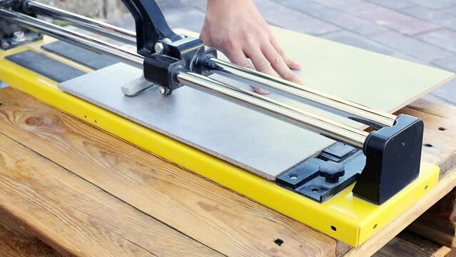 Construction worker cuts ceramic tile using tile cutting hand machine in slow motion. Construction and repair concept