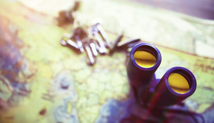 Binoculars and map on wooden table. Top view traveler essentials concept.