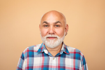 Obraz premium Close-up studio portrait of senior man looking at camera. Golden age grandfather. Bearded old aged man, head and shoulders portrait.