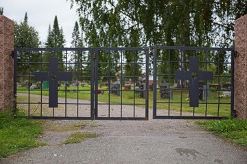 Entrance to cemetery with old wrought iron gate with crosses.