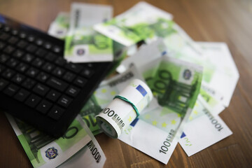 Computer keyboard and a scattering of 100 euro bills on the table. The work of a programmer and blogger on the Internet.