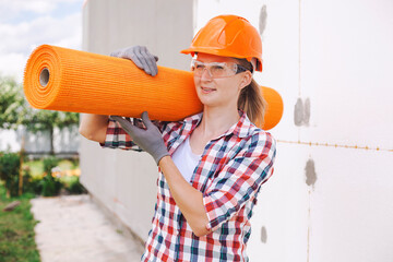 The woman with rolls of reinforcing fiberglass. Insulation of the house with polyfoam board on the...