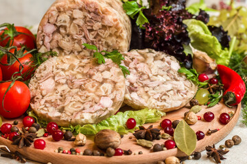 Homemade headcheese on a round cutting board with  vegetables