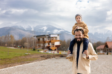 Close-up shot of a Caucasian smiling male with little child with the upside-down house in the...