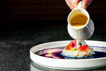 chef cooking Tartar with a scallop on a plate with sauce