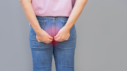 Back view of woman stand hand holding her bottom because having Abdominal pain and Hemorrhoids