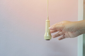 Cropped image of hand hold or pressing emergency nurse call button over white wall background.