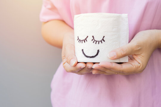 Cropped image hands of women holding a white toilet paper with smiley face.