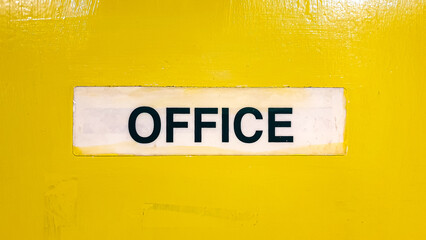 Close up of vintage retro office sign in capital letters with  black text on a bright yellow hand painted door
