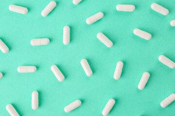 Vitamin capsules on turquoise background, flat lay