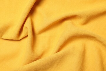 Texture of soft yellow crumpled fabric as background, top view