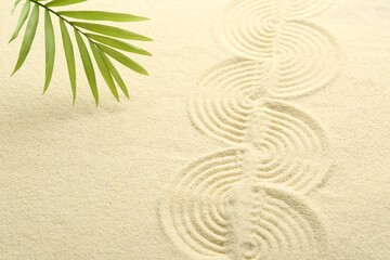 Fototapeta na wymiar Zen rock garden. Wave pattern and green leaf on beige sand