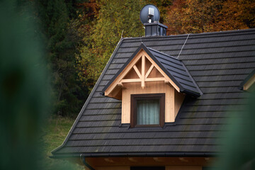 A cozy home nestled at the forest’s edge with a detailed wooden window accentuating its architectural beauty.