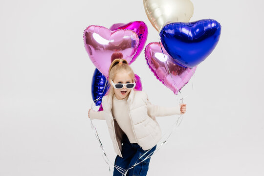 Cute girl dancing on a white background with balloons. The concept of children's theater productions and developing acting circles and children's parties.