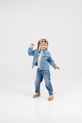 Cheerful little girl in modern clothes having fun, performing freestyle dance moves, on isolated white background. Children's clothing advertising concept
