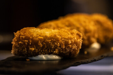 Close-up of a homemade croquette with a cheese base on a slate plate