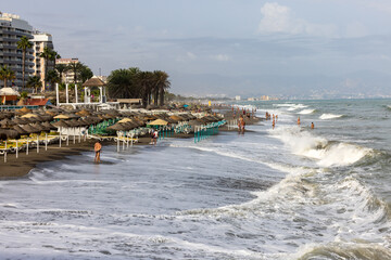 Foamy sea waves on the sandy beach of Bajondillo in Torremolinos, Malaga, Costa del Sol, Spain