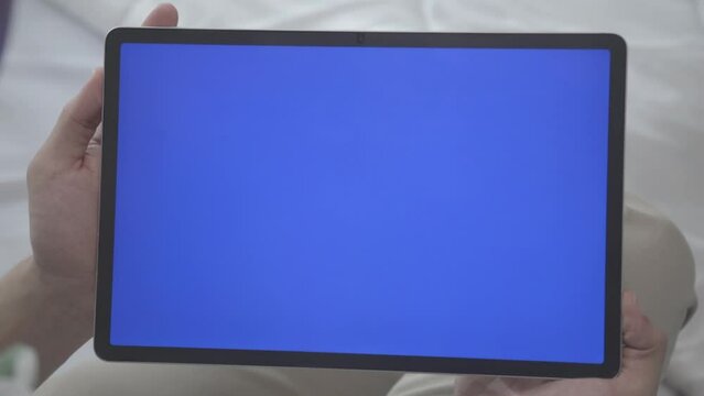 Asian Man Holding Tablet with Blue Screen in Close up Shot