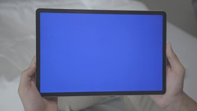 Asian Man Holding Tablet with Blue Screen in Straight Shot