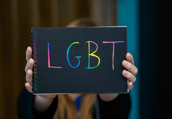 Kobieta trzyma kartkę z kolorowym napisem LGBT - obrazy, fototapety, plakaty
