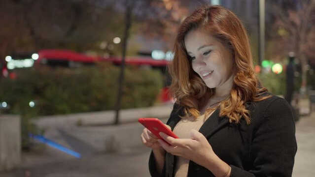 Medium lateral shot of a pretty woman with the smartphone and black coat and light brown dress