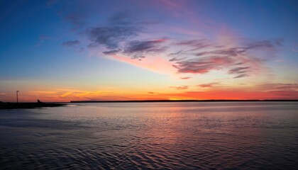 A wide-angle image of the sunset beyond the bay in Delaware showing dynamic red, orange, and blue colors